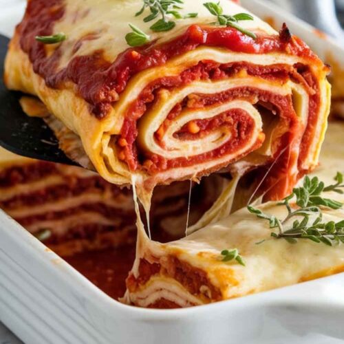 Lasagna roll-ups covered in marinara sauce and fresh basil leaves.